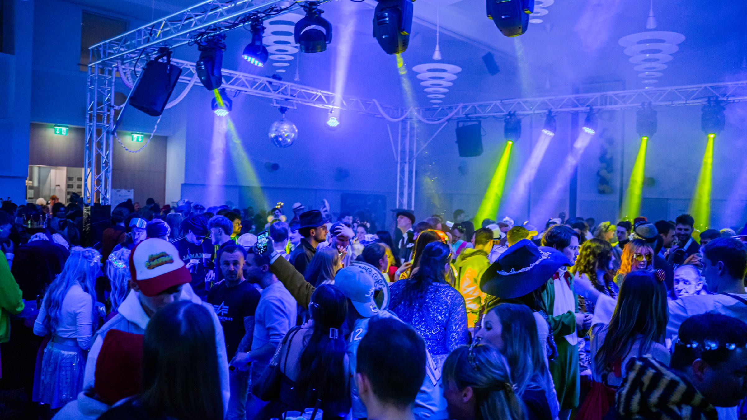 Volle Tanzfläche unter bunter Lichttechnik bei einer Faschingsparty