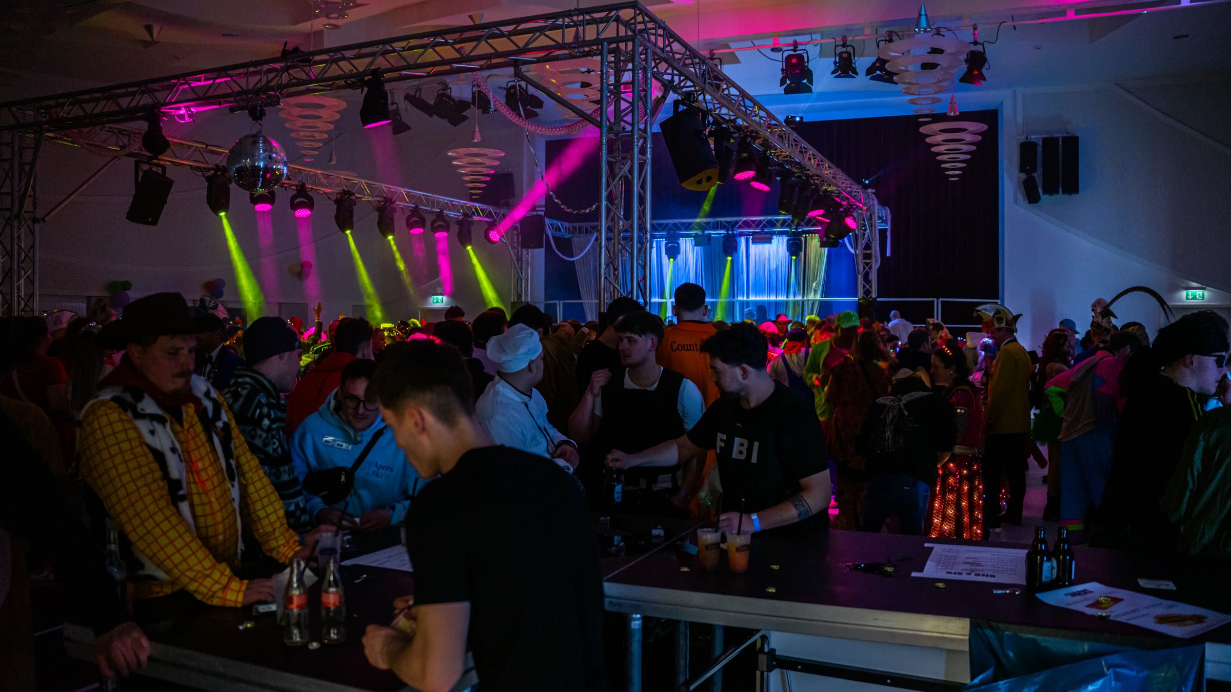 Volle Tanzfläche mit Lichttechnik und Bar auf einer Veranstaltung