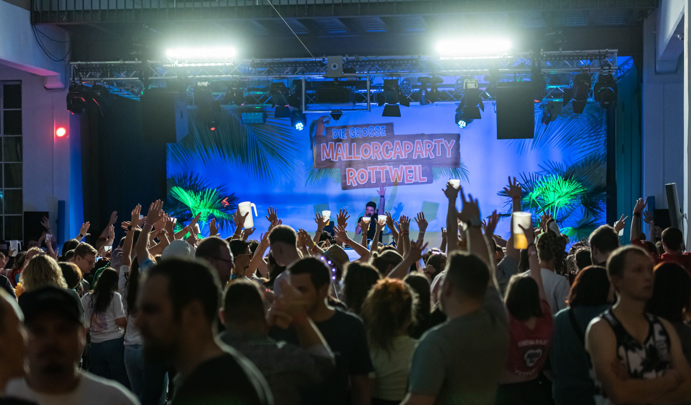 Feiernde Gäste vor der dekorierten Bühne der Mallorcaparty